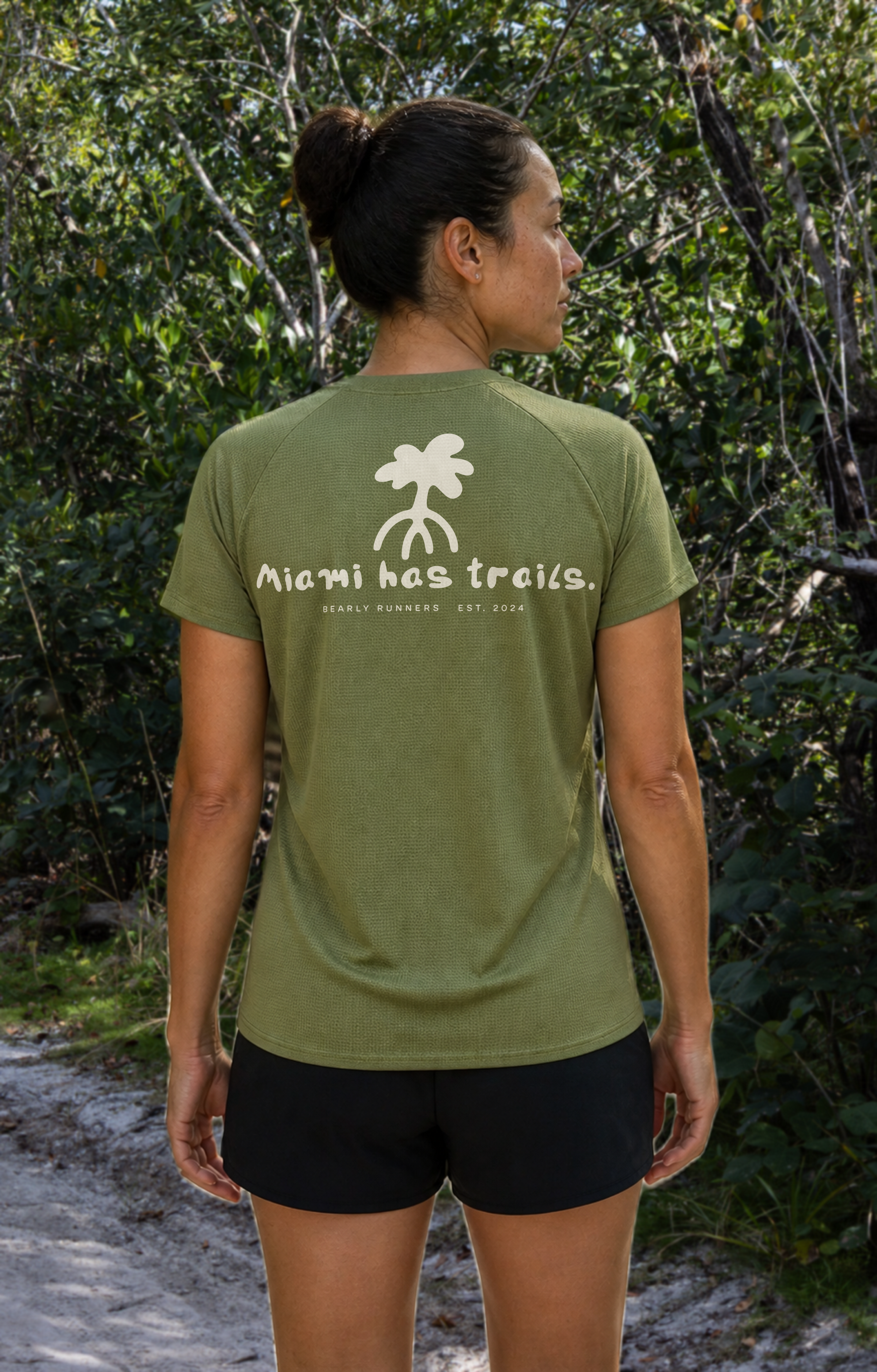 Women’s Fern Green MIAMI HAS TRAILS Trail Tee on a model, back view with palm graphic and Miami has trails print.